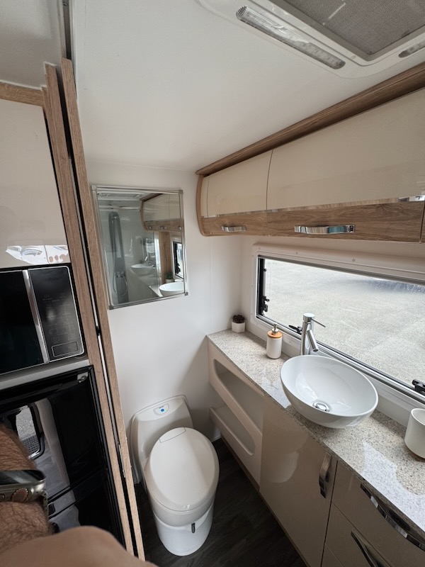 Looking towards the back left of the ensuite, is the small cassette loo. A better view of the cabinets on the back wall as well as the porcelain sink.